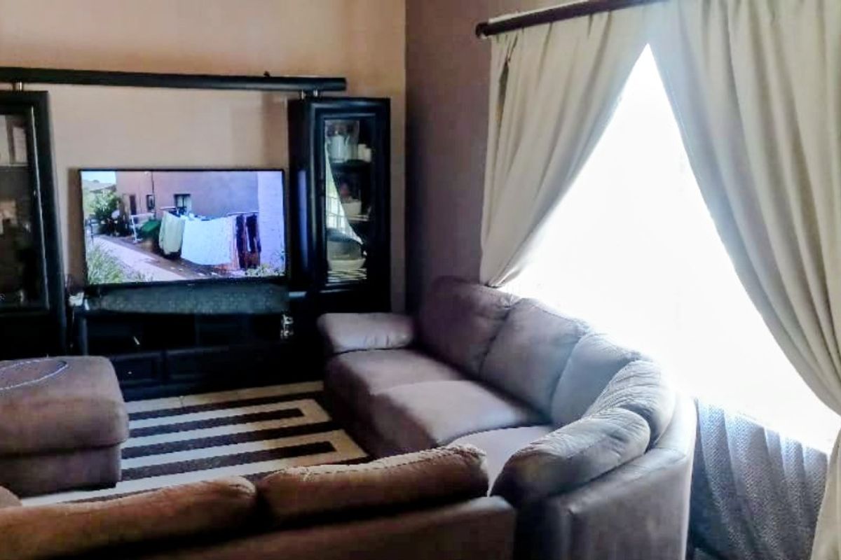 A cozy living room featuring a large window with curtains and a dedicated media wall unit.