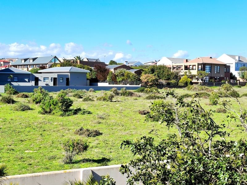 A view of a vacant residential plot with surrounding established neighborhood homes and boundary walling.