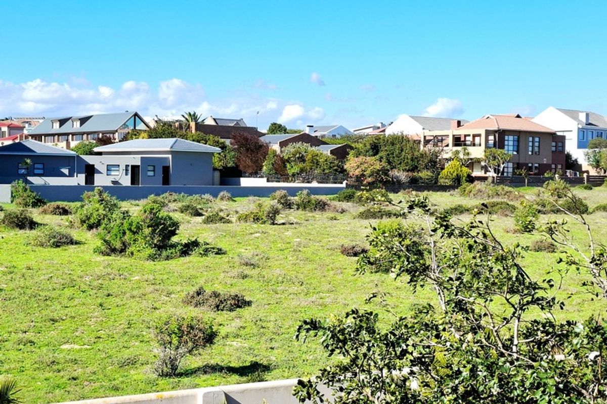 A view of a vacant residential plot with surrounding established neighborhood homes and boundary walling.