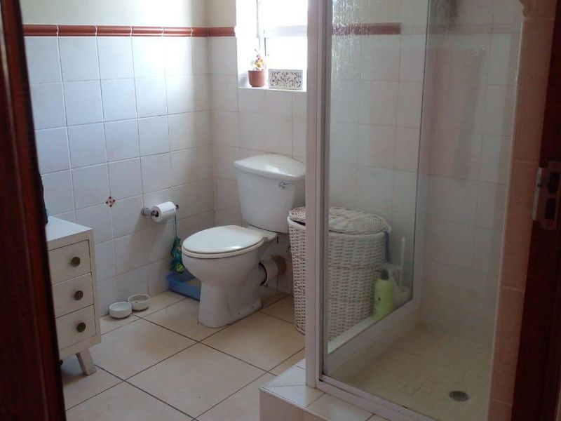 A functional bathroom featuring a shower enclosure, toilet, and neutral wall and floor tiling, offering a clean and practical layout.