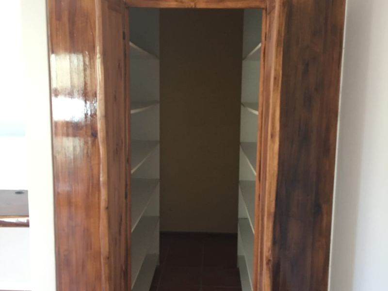 A functional walk-in pantry or scullery area featuring built-in shelving and tiled flooring, providing ample storage space.