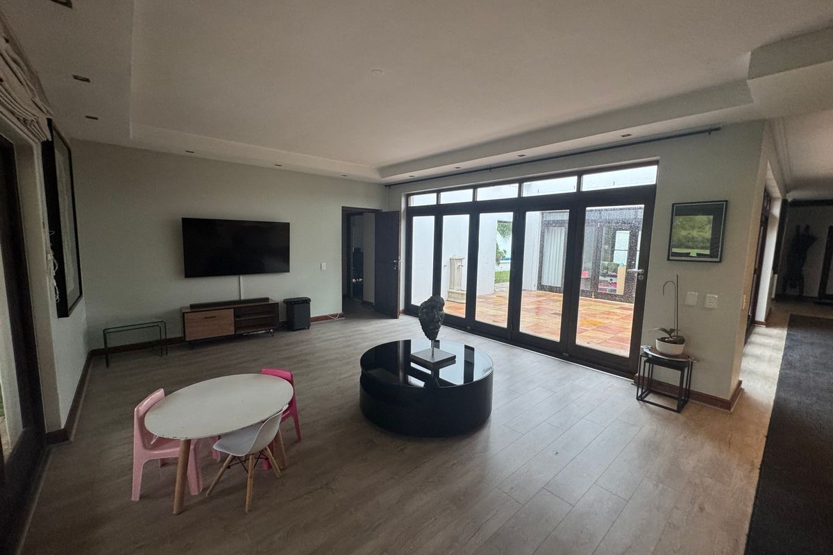 Spacious living room featuring light wood-look flooring, recessed ceiling lighting, and large folding glass doors providing seamless access to the outdoor patio area.