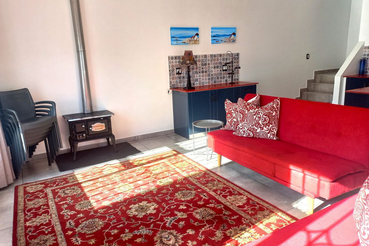 A living area featuring a cast iron wood-burning stove with a flue, tiled flooring, and a built-in blue cabinetry unit with decorative backsplash tiling.