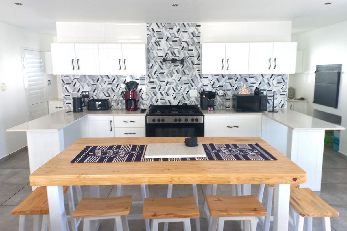 Modern kitchen featuring white cabinetry, stone countertops, a geometric tiled backsplash, and a built-in gas stove with an extractor fan.