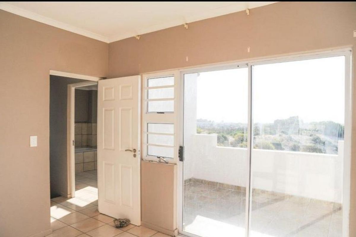 A bedroom featuring tiled flooring, a built-in door, and large sliding glass doors providing access to an outdoor balcony area.