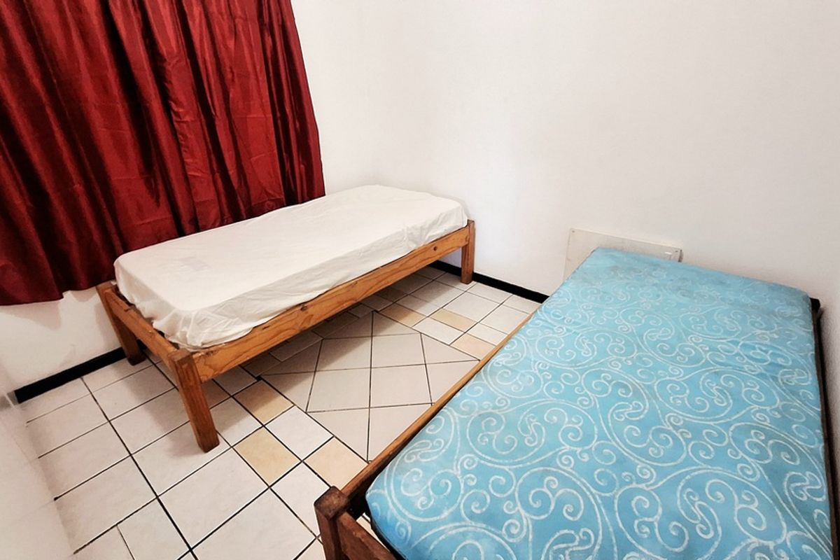 A compact bedroom featuring tiled flooring and a simple layout, suitable for a guest room or children's bedroom.