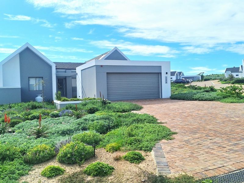 Modern single-story residence featuring a paved driveway, integrated garage, and well-maintained landscaped garden in a contemporary estate setting.