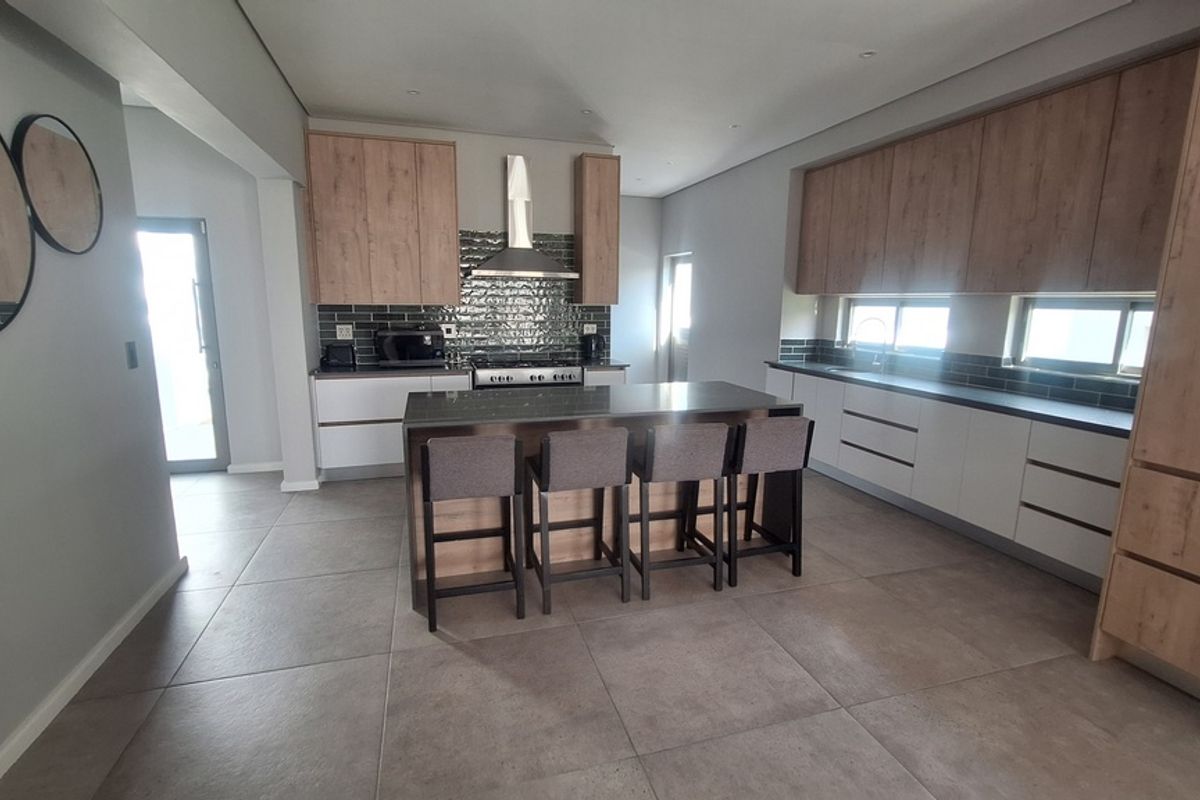 Modern kitchen featuring a central island, two-tone cabinetry, subway tile backsplash, and high-quality tiled flooring with integrated appliances.