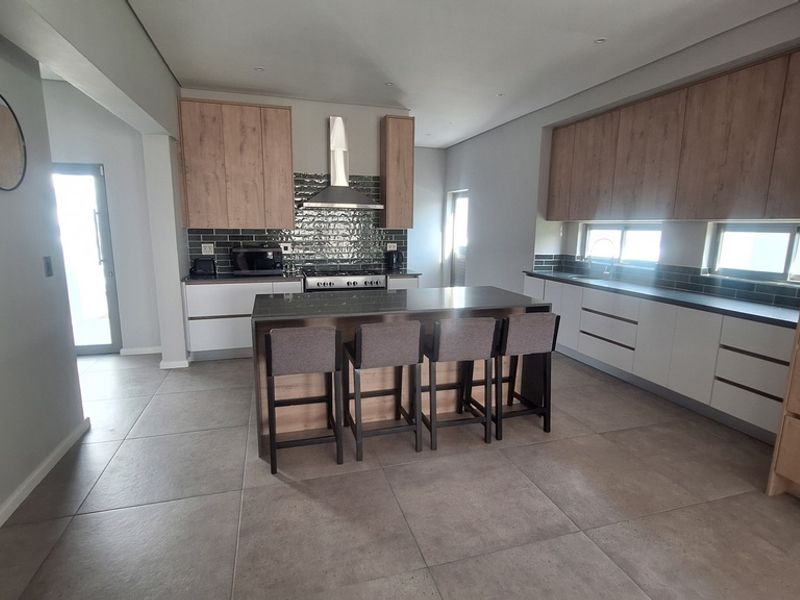 Modern kitchen featuring a central island, two-tone cabinetry, subway tile backsplash, and high-quality tiled flooring with integrated appliances.