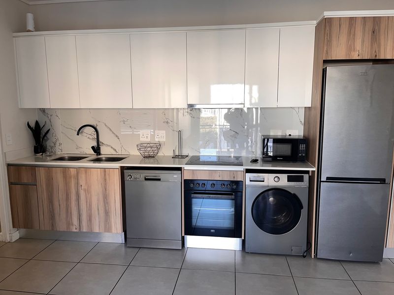 Modern kitchen featuring sleek white and wood-grain cabinetry, marble-look splashback, integrated appliances, and high-quality finishes throughout.