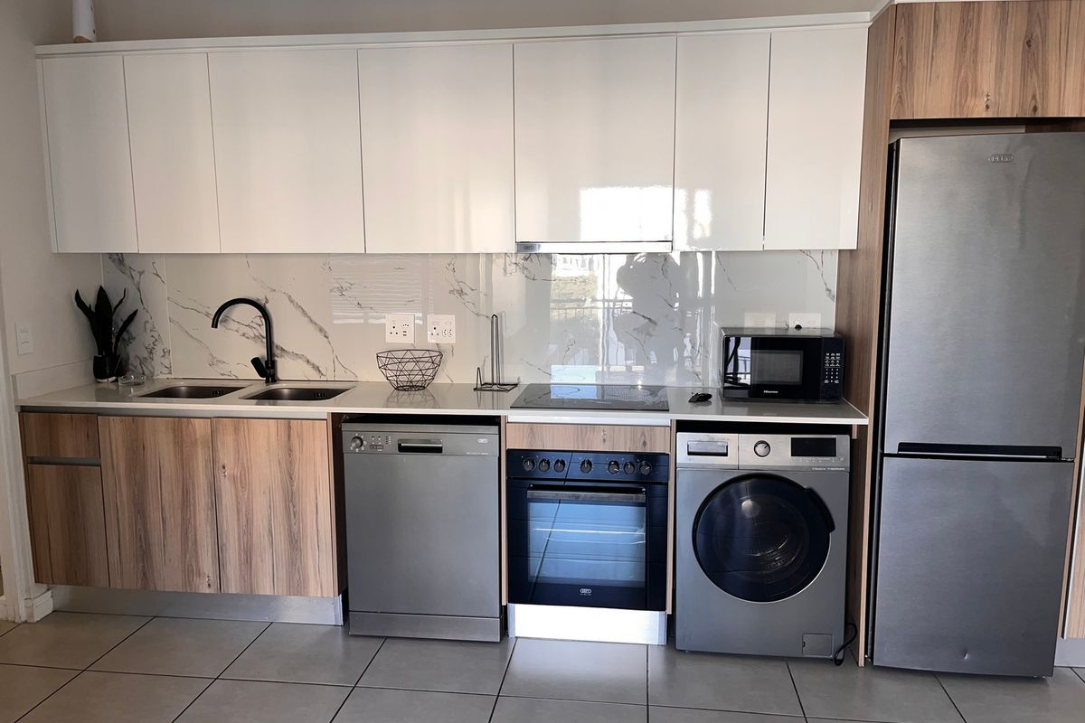 Modern kitchen featuring sleek white and wood-grain cabinetry, marble-look splashback, integrated appliances, and high-quality finishes throughout.