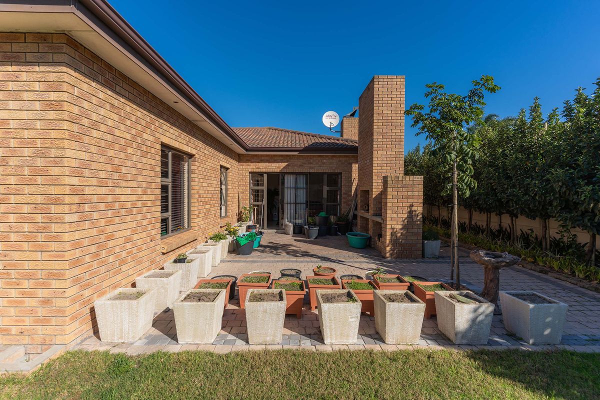 Rear exterior view featuring a paved patio area with a built-in brick fireplace and direct access to the home.