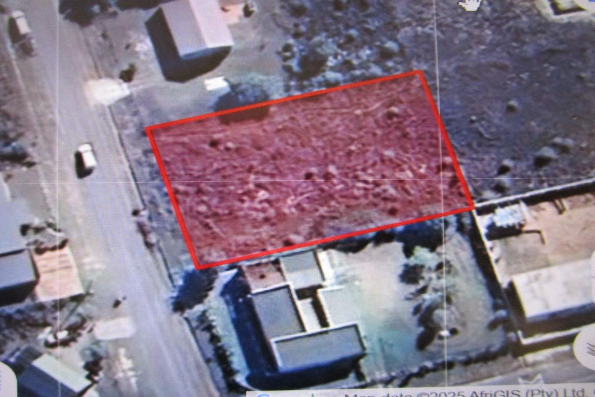 An aerial view of a vacant residential plot outlined in red, showing the surrounding neighborhood and street access.