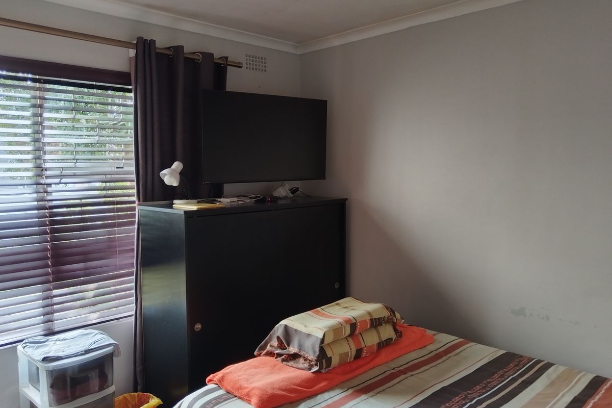 A bedroom featuring a window with fitted blinds and neutral wall finishes.