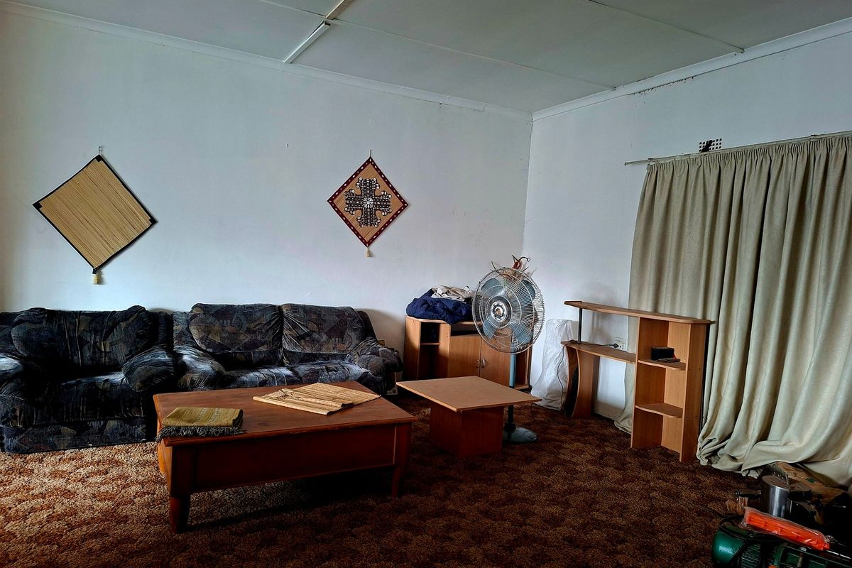 A living room featuring dated wall-to-wall carpeting and standard ceiling panels, offering a blank canvas for potential interior updates and modernization.