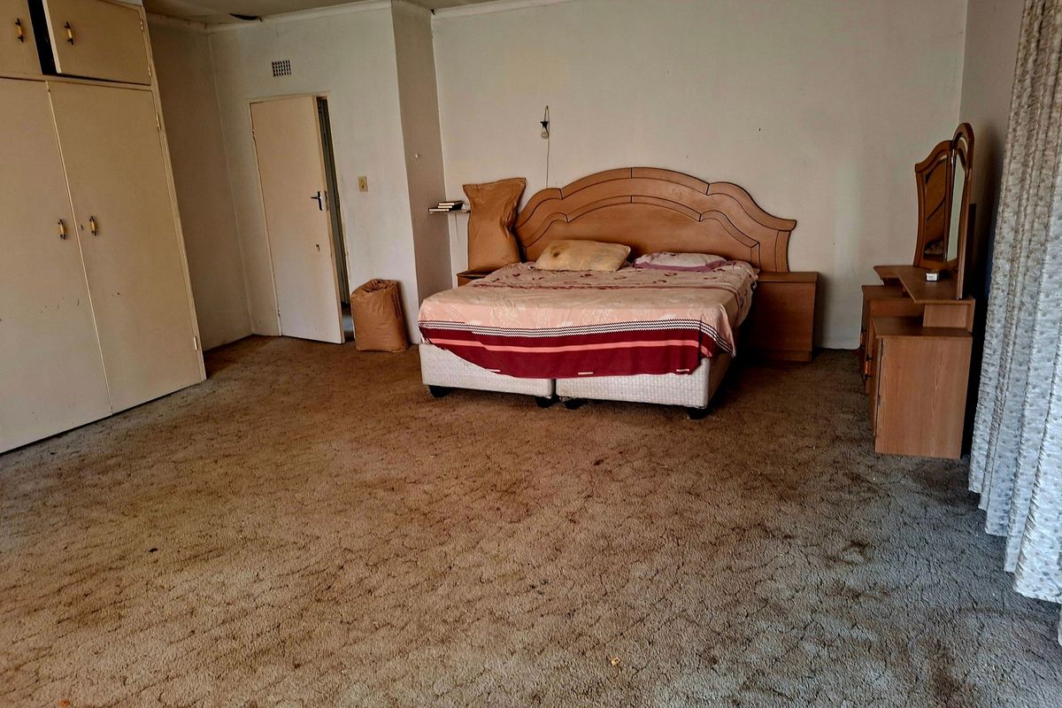Spacious bedroom featuring built-in cupboards, carpeted flooring, and direct access to an adjoining room.