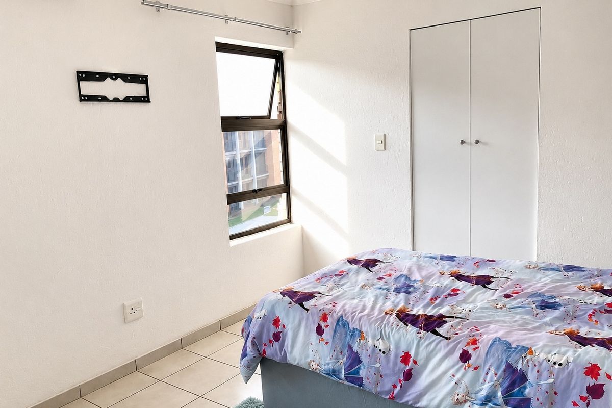 A bedroom featuring tiled flooring, a built-in wardrobe, and a window with natural light.