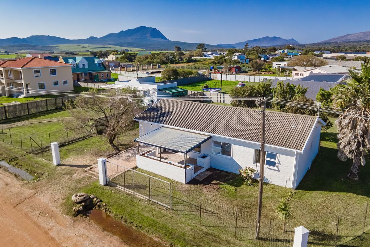 Aerial view of a detached single-story house featuring a tiled roof, covered patio area, and surrounding garden in a rural residential setting.