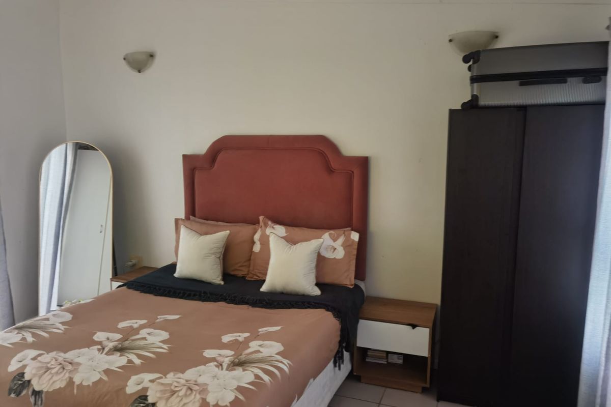 A bedroom featuring tiled flooring and wall-mounted light fixtures.