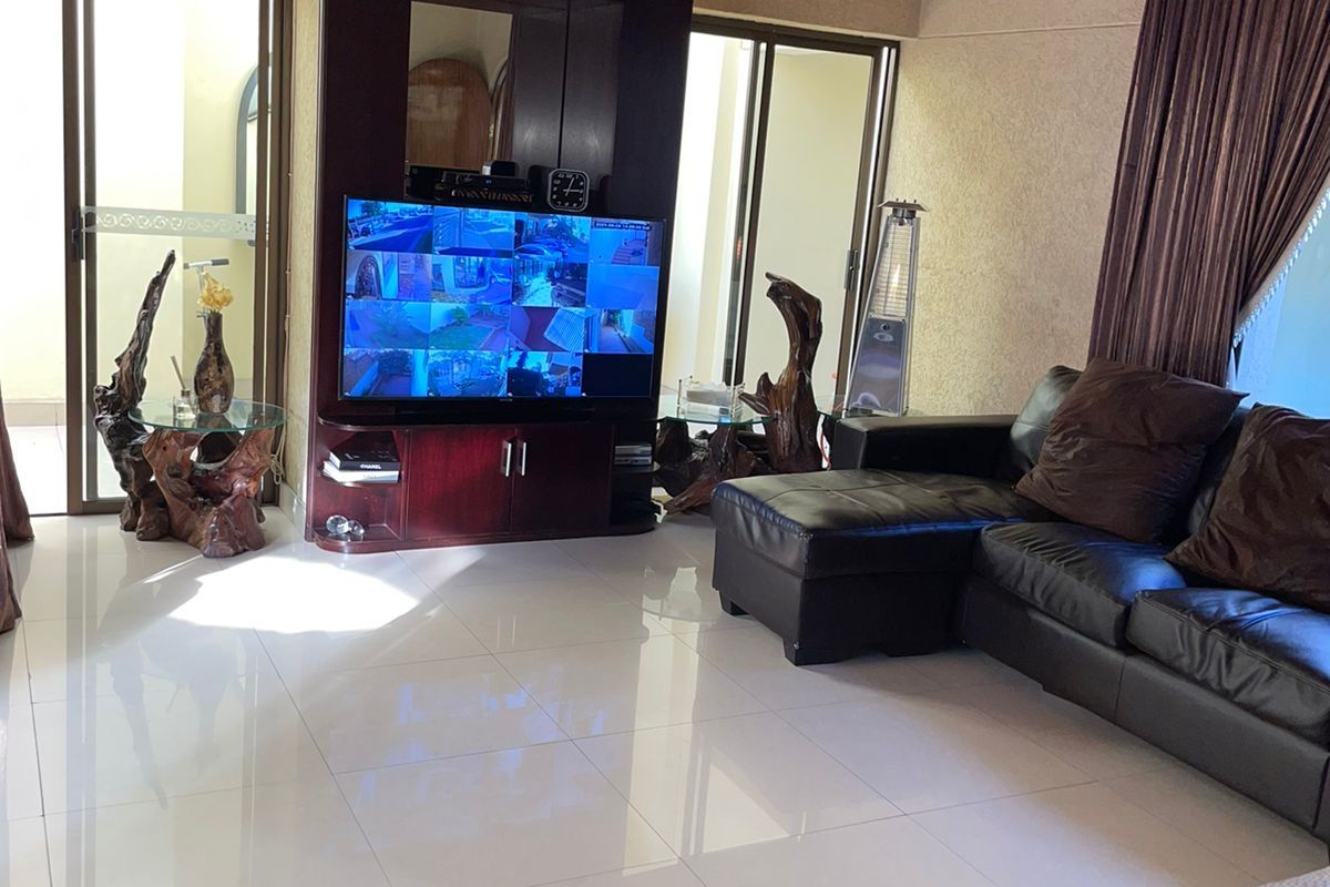 Spacious living room featuring polished floor tiles, a built-in media unit, and large sliding glass doors providing access to the outdoor area.