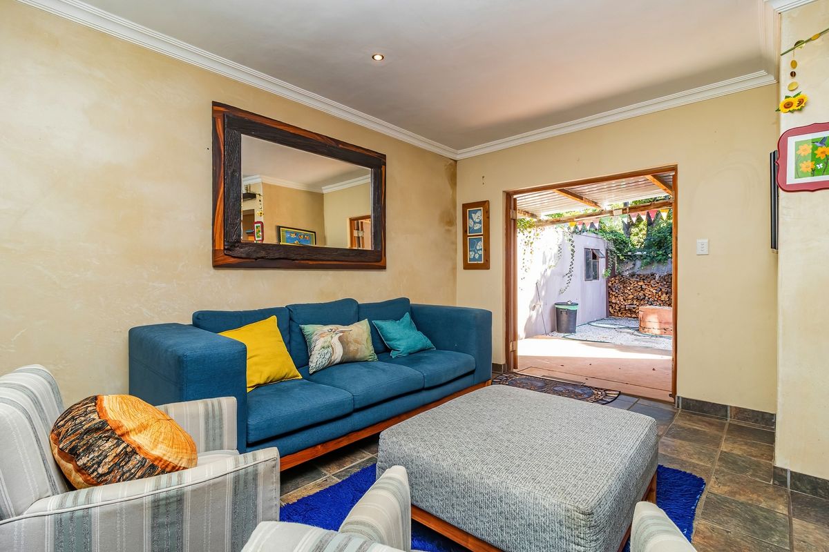Living room featuring tiled flooring and direct access to an outdoor patio area, with visible wall finish wear requiring attention.
