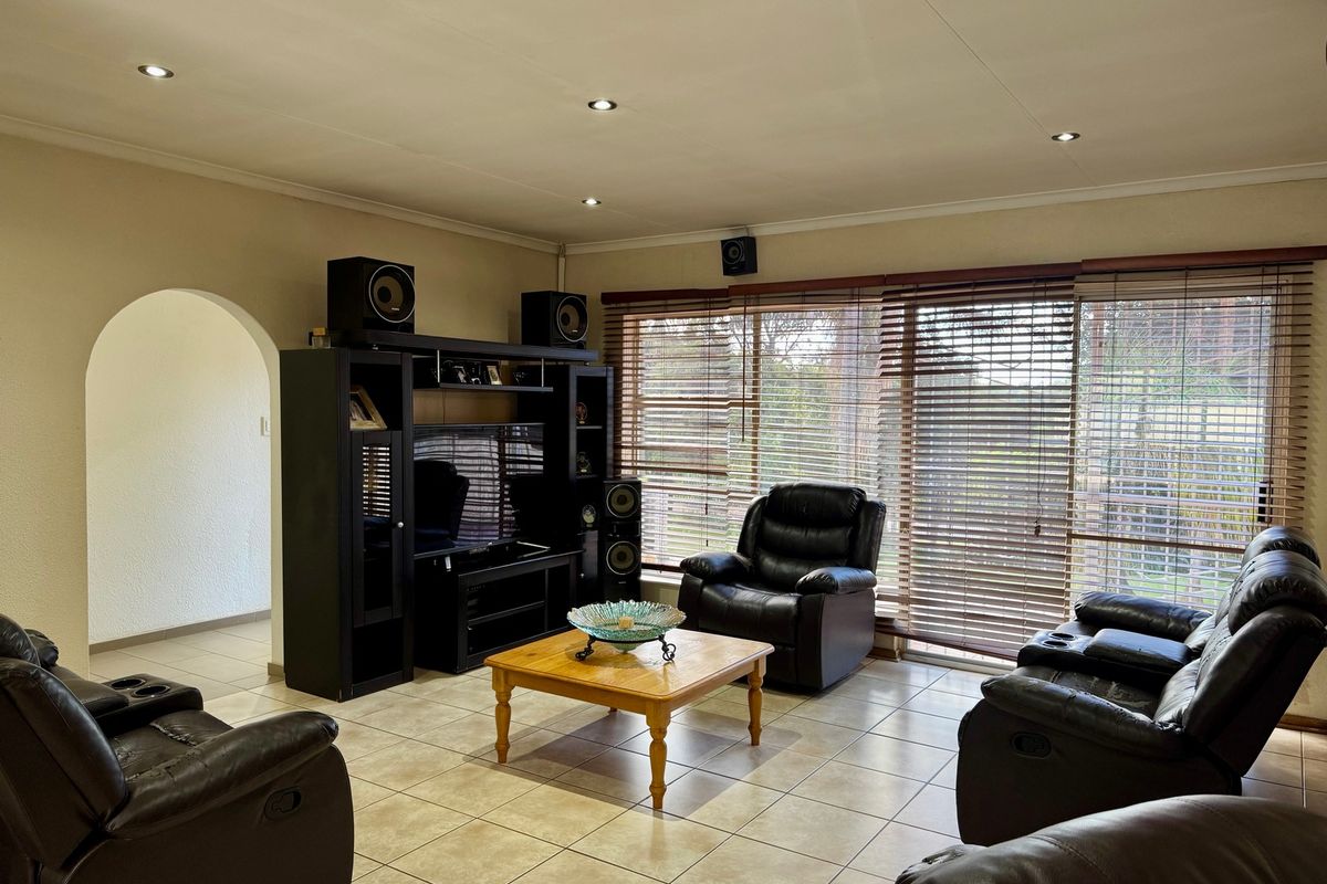 Spacious living room featuring tiled flooring, recessed downlighting, and large windows with fitted blinds, providing ample natural light and access to the exterior.