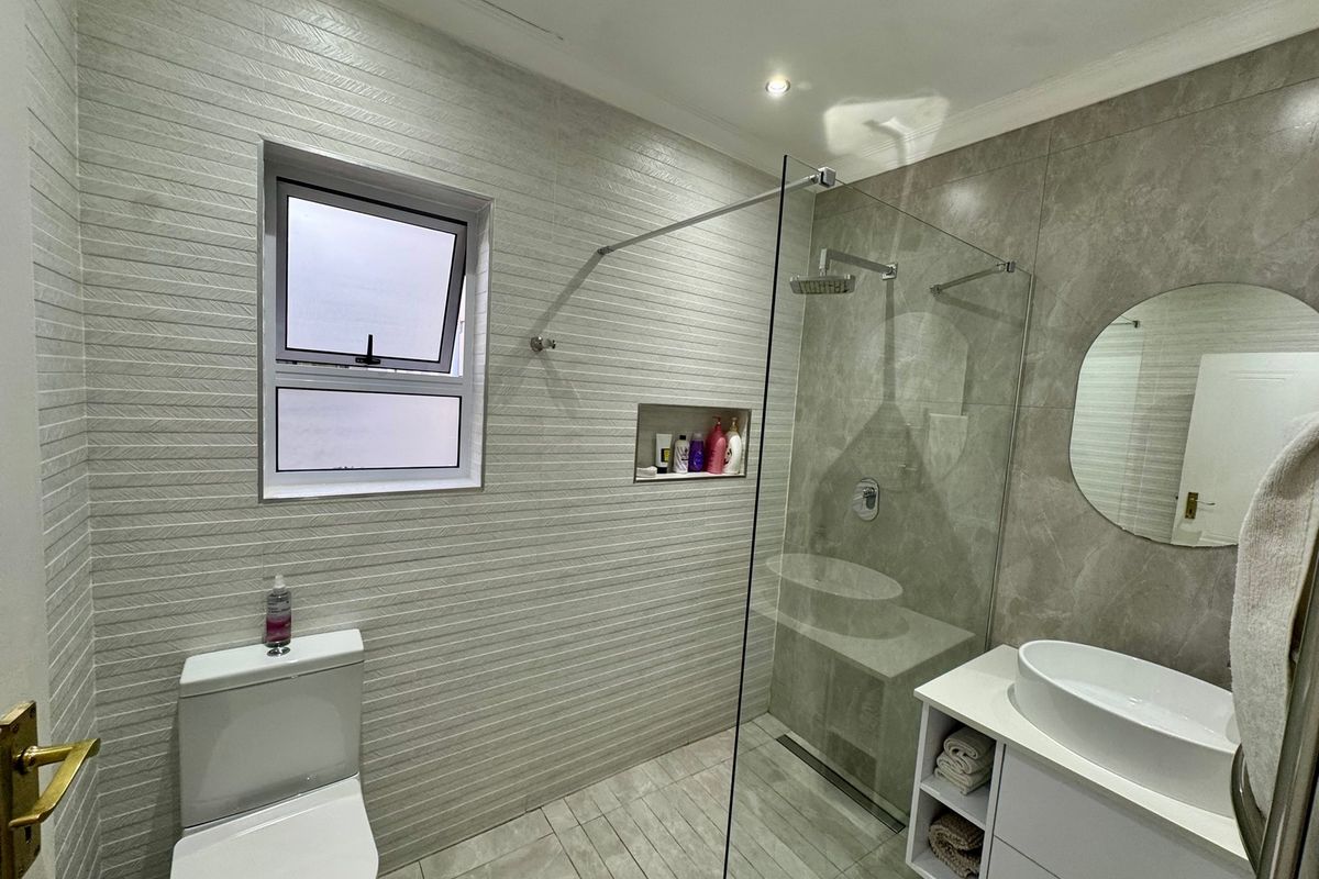 Modern bathroom featuring a glass-enclosed walk-in shower, wall-mounted vanity with vessel sink, and contemporary tiled walls.