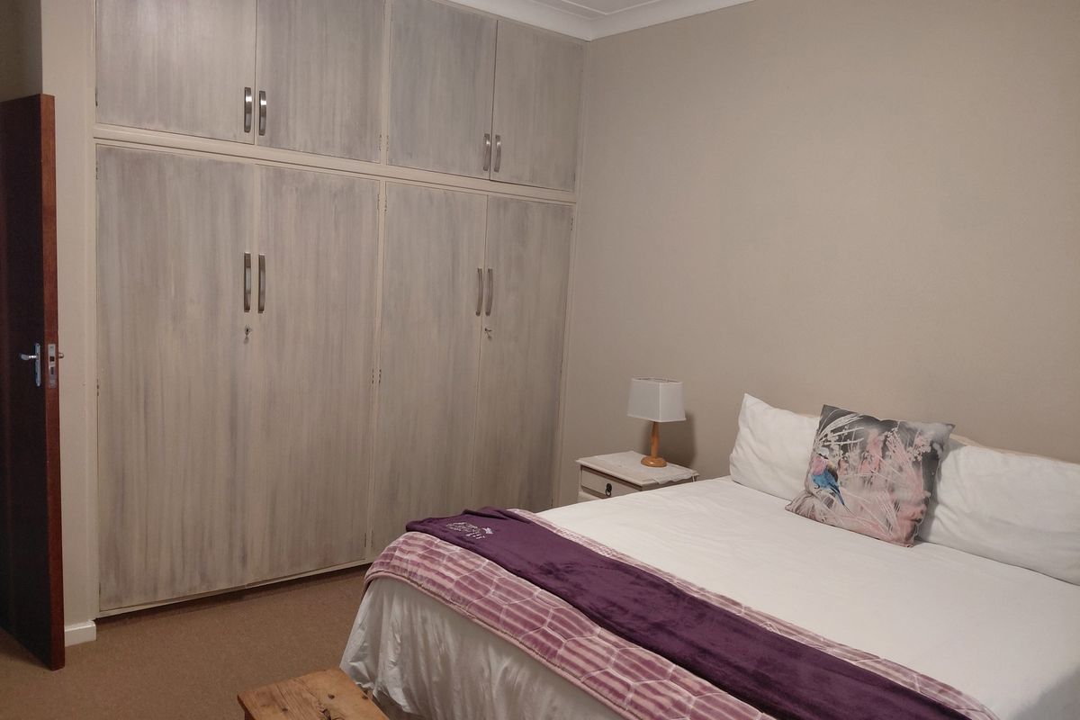 A bedroom featuring built-in floor-to-ceiling wardrobes with a light wood-grain finish and neutral wall tones.