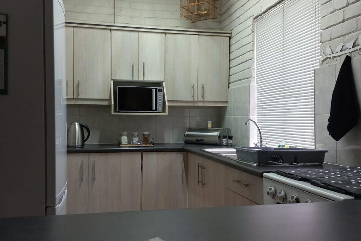 Functional kitchen featuring light wood-finish cabinetry, dark countertops, a built-in microwave, and a double sink with a window view.