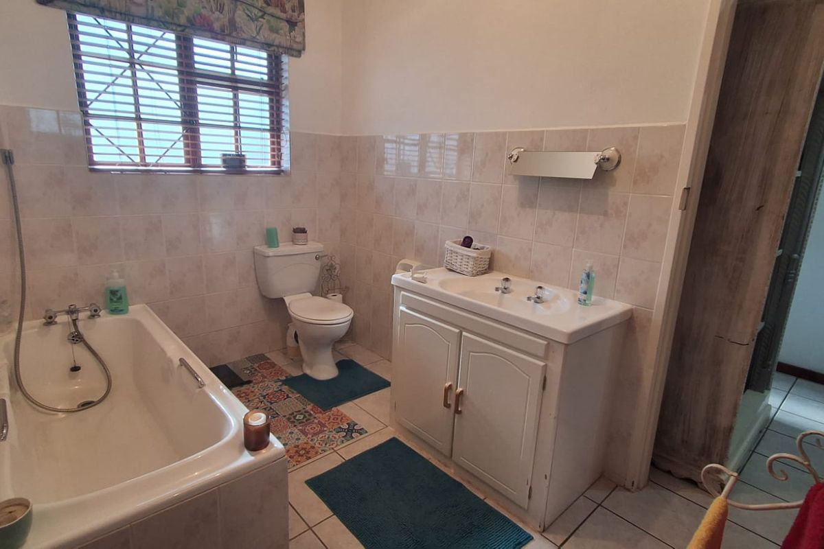 A functional bathroom featuring a built-in vanity, bathtub, and toilet with neutral wall tiling and tiled flooring.