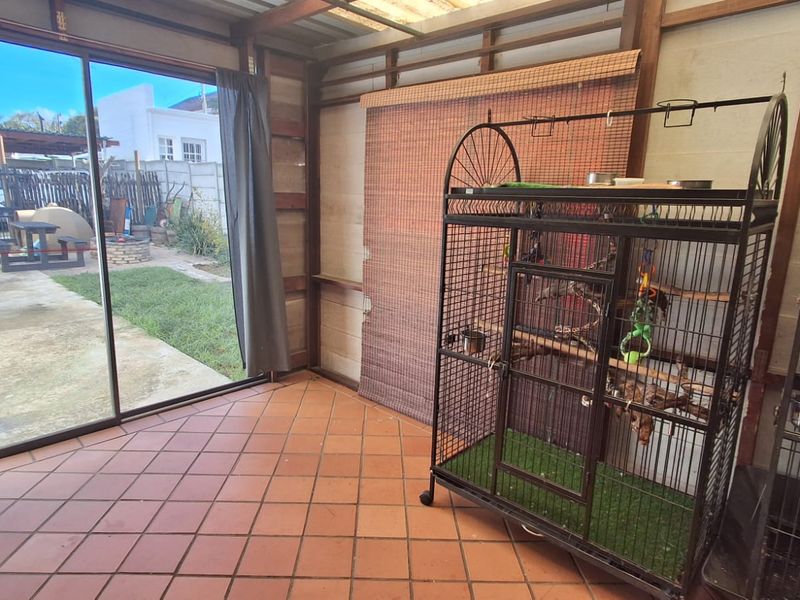 Enclosed patio area featuring terracotta floor tiles, exposed timber structure, and large sliding glass doors providing direct access to the rear garden.