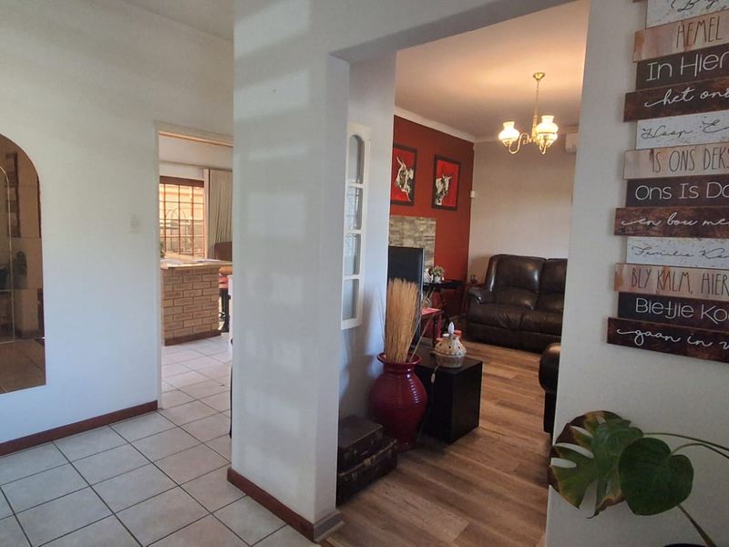 A bright hallway connecting the living area and kitchen, featuring a mix of tiled and laminate flooring with a distinct architectural archway.