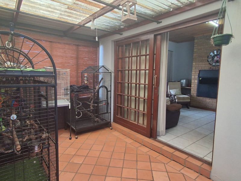 Covered patio area featuring terracotta tile flooring and a timber sliding door providing access to the interior living space with a brick fireplace.
