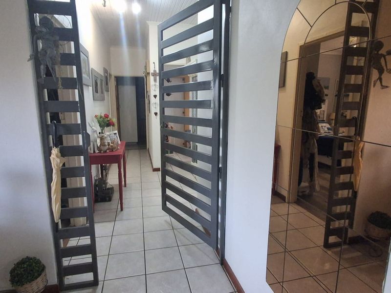 A tiled hallway featuring a metal security gate and decorative mirrored wall paneling, providing access to various rooms within the home.