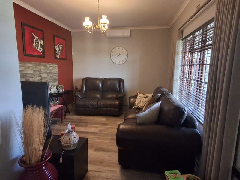 A comfortable living room featuring laminate flooring, a feature wall with stone-cladding detail, and a wall-mounted split-system air conditioner.