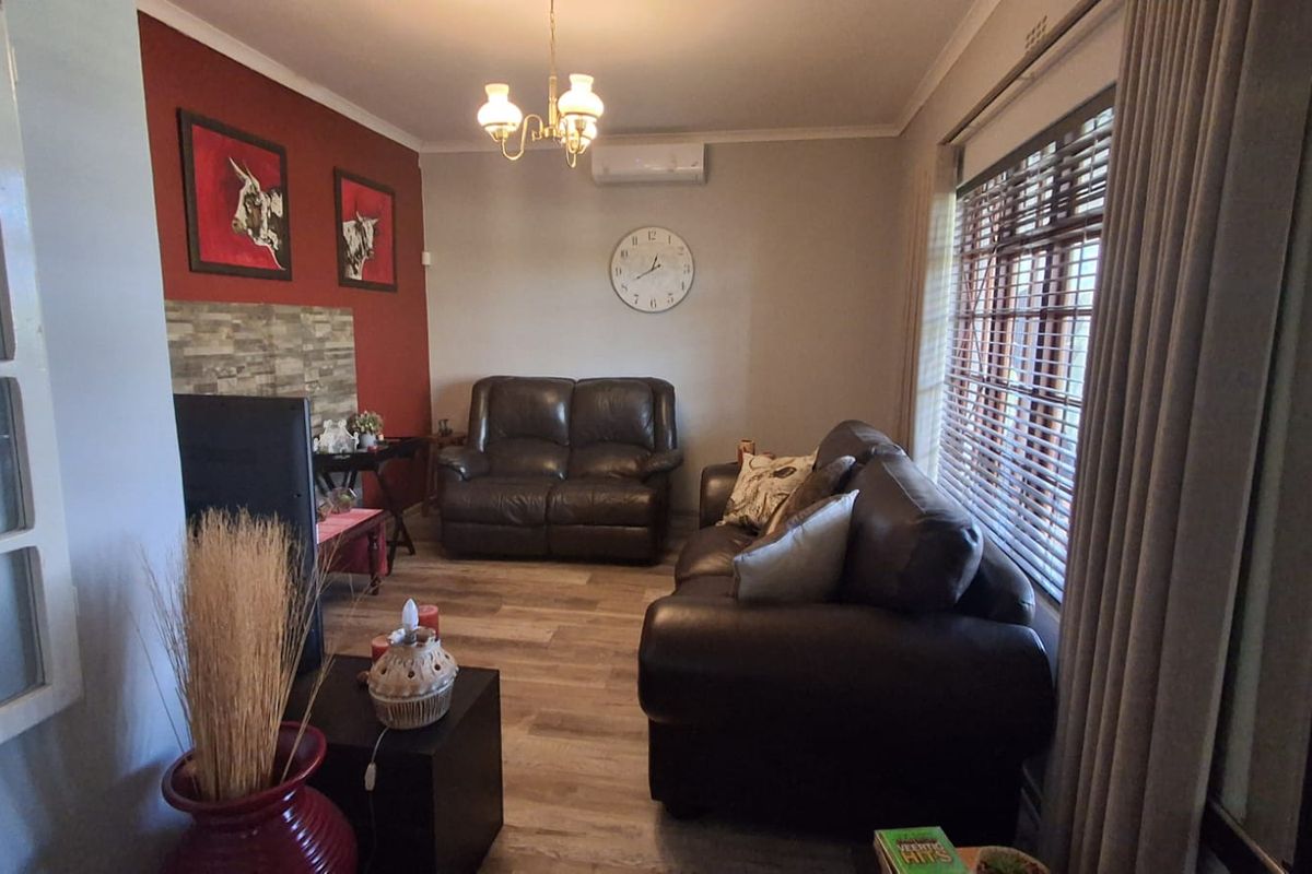 A comfortable living room featuring laminate flooring, a feature wall with stone-cladding detail, and a wall-mounted split-system air conditioner.