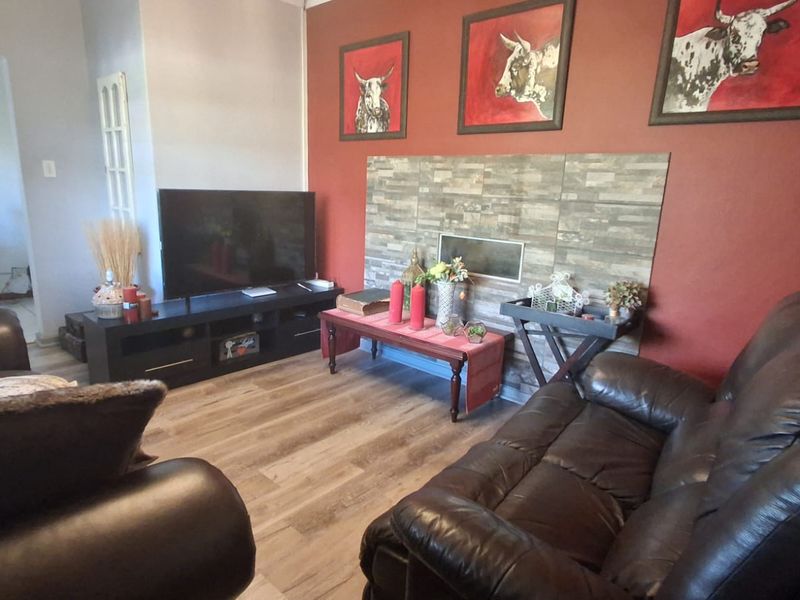 A living room featuring a stone-clad fireplace feature wall and modern laminate wood flooring.
