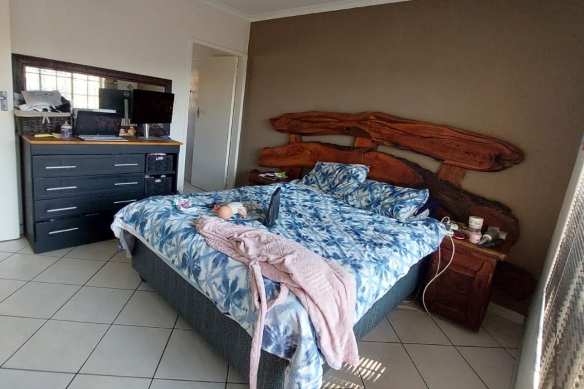 A bedroom featuring tiled flooring, a ceiling fan, and a built-in wooden headboard feature.
