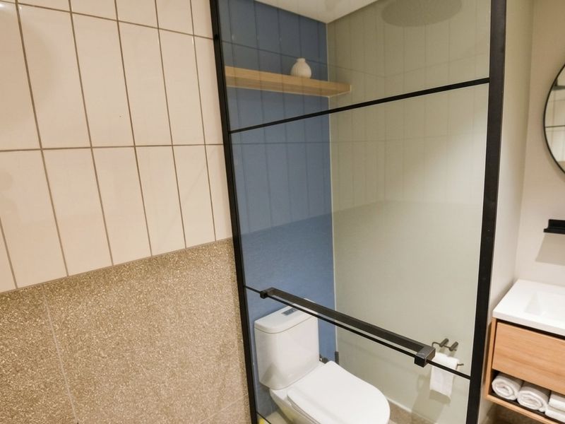 Modern bathroom featuring a walk-in shower with black-framed glass screen, wall-mounted toilet, and a contemporary vanity unit with integrated basin.