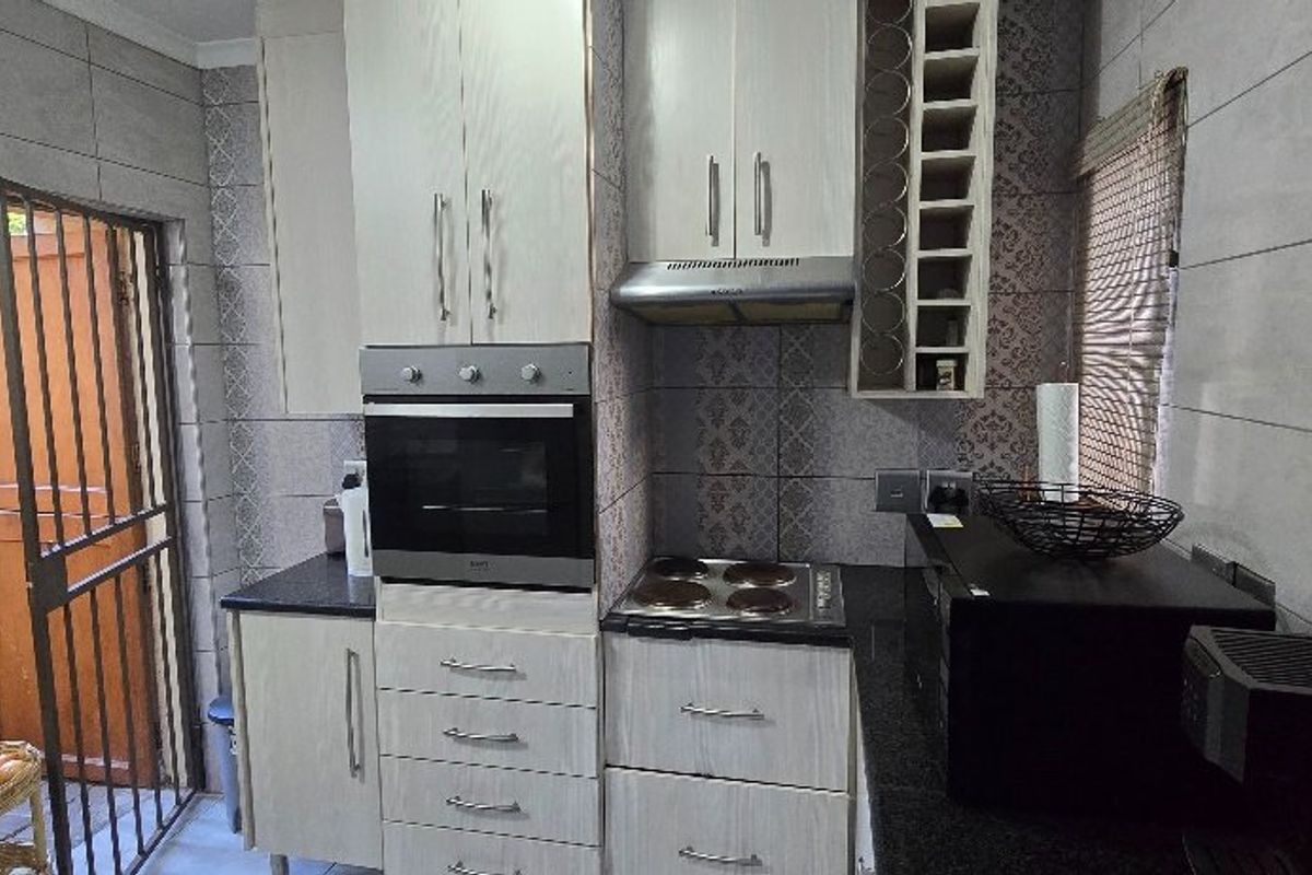 Compact kitchen featuring built-in cabinetry, integrated oven, electric hob, extractor fan, and direct access to an outdoor area.