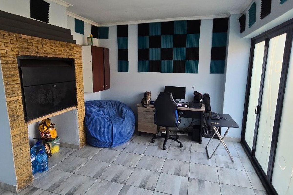 A multi-purpose room featuring a built-in indoor braai with stone cladding, tiled flooring, and large sliding glass doors providing natural light.