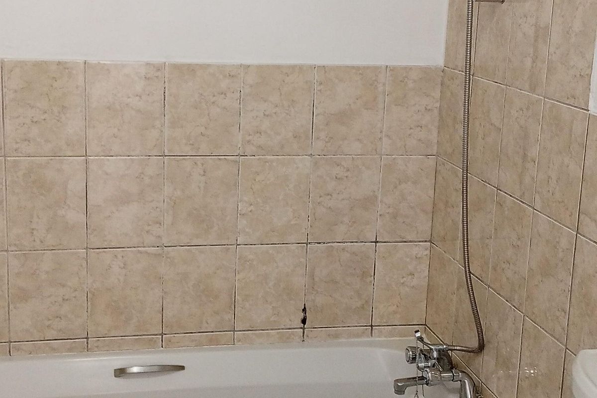 A functional bathroom featuring a bathtub with a handheld shower attachment and tiled wall finishes.