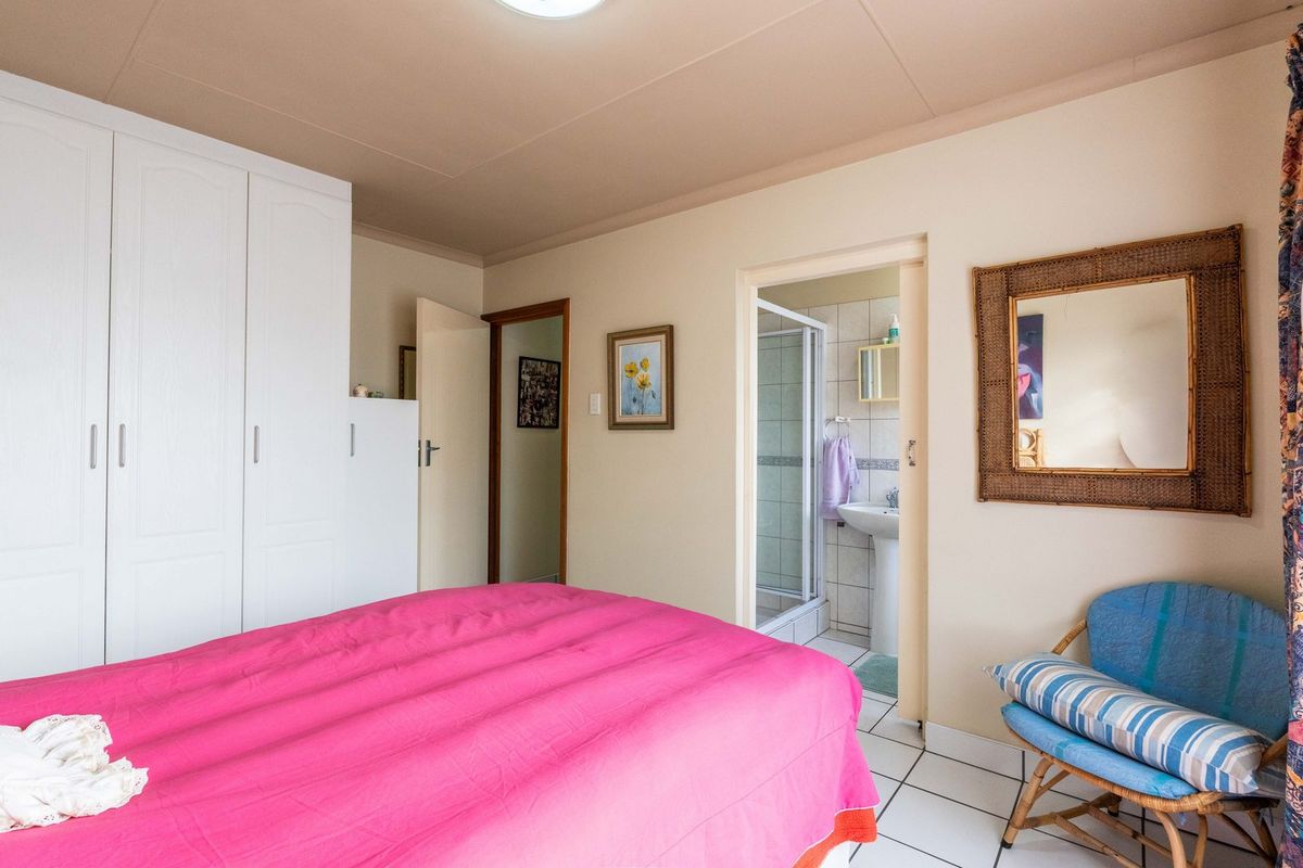 A bedroom featuring built-in wardrobes and an en-suite bathroom with a shower, finished with tiled flooring.