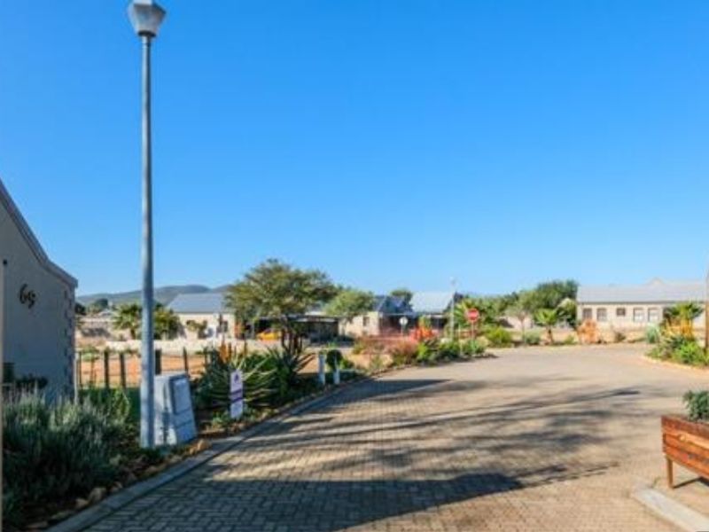 A view of the paved street and surrounding residential neighborhood approach, featuring established landscaping and clear access to the property.