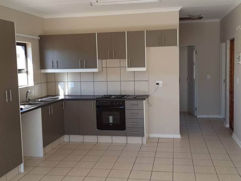 A functional kitchen featuring built-in cabinetry, a built-in oven with electric hob, tiled backsplash, and neutral tiled flooring in an open-plan layout.
