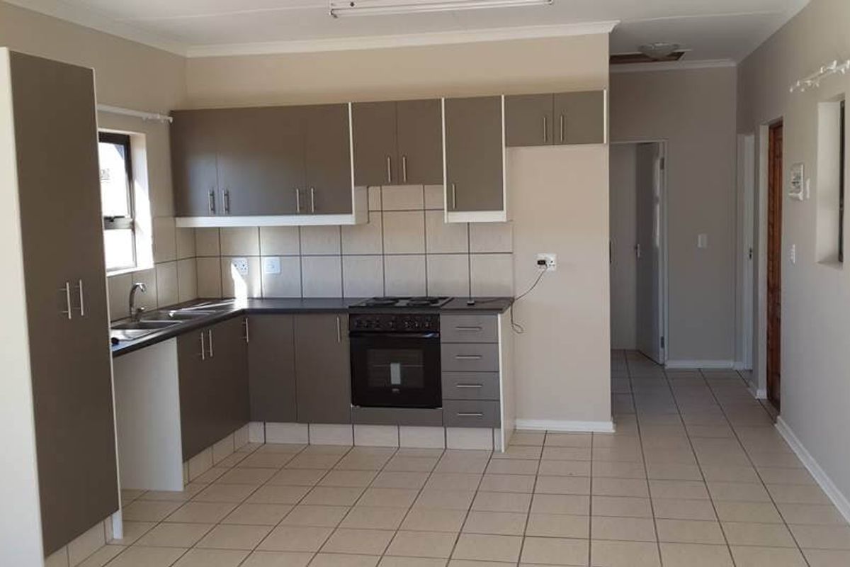 A functional kitchen featuring built-in cabinetry, a built-in oven with electric hob, tiled backsplash, and neutral tiled flooring in an open-plan layout.