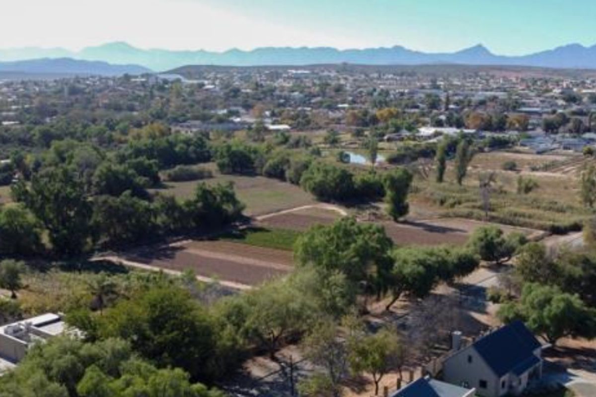 An aerial view of the property grounds, surrounding landscape, and neighborhood with mountain views in the distance.