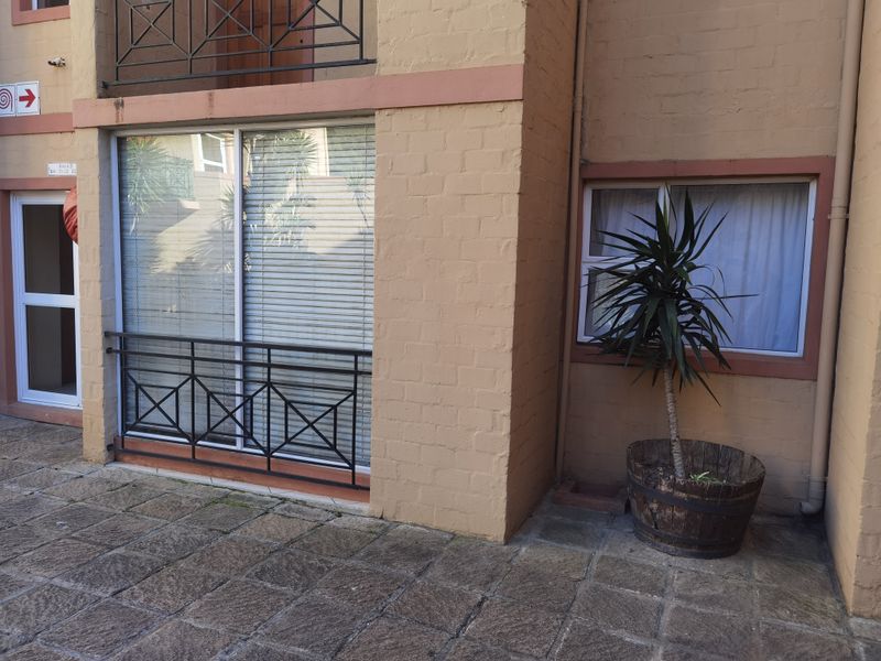 Ground floor apartment exterior featuring a paved patio area, sliding glass door access, and metal balustrades against a brick facade.