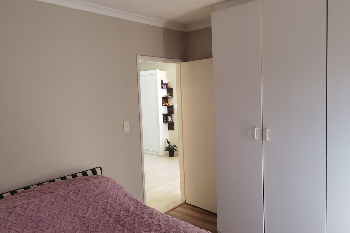 A bedroom featuring built-in cupboards and neutral wall finishes, with a doorway leading to an adjacent room.