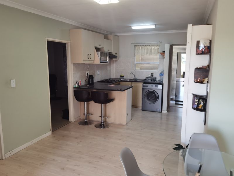 Open-plan kitchen featuring built-in cabinetry, laminate countertops, a hob with extractor fan, and a dedicated space for a washing machine.